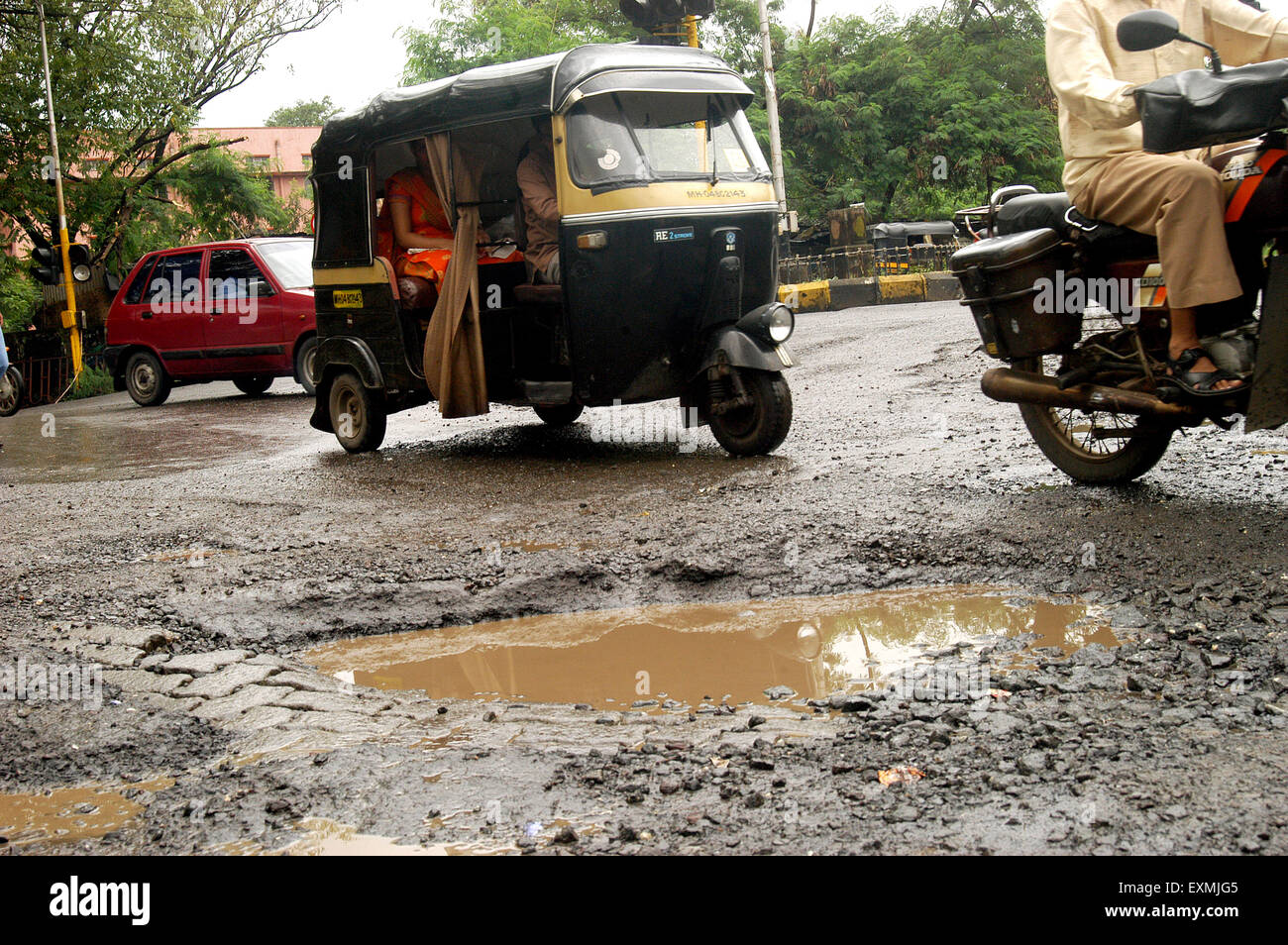 Cars autos and bikes drive on road with pot holes Thane city Bombay Mumbai Maharashtra India Asia Stock Photo