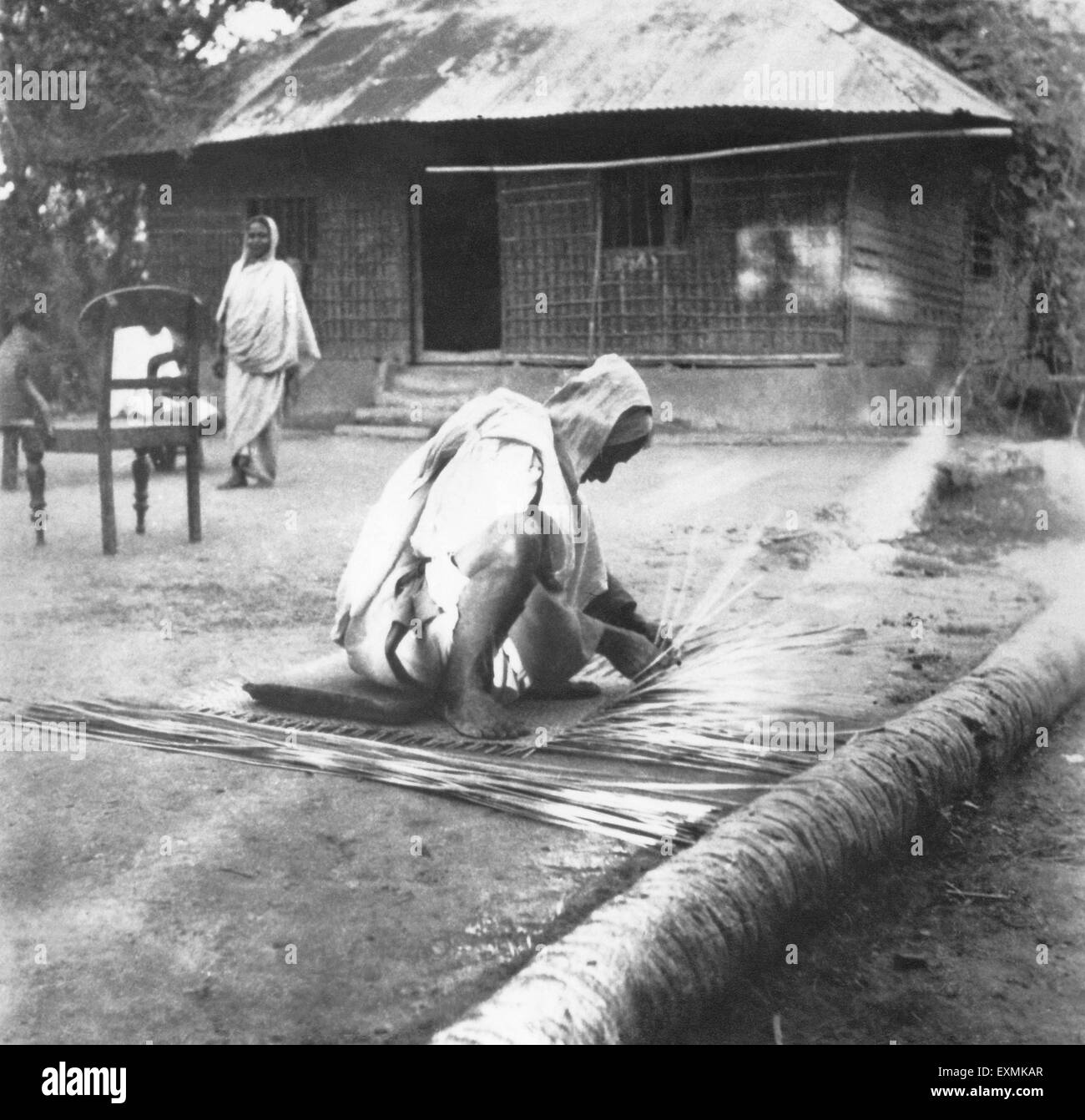 Mahatma Gandhi ; preparing a straw mat in a riot stricken village in Noakhali East Bengal