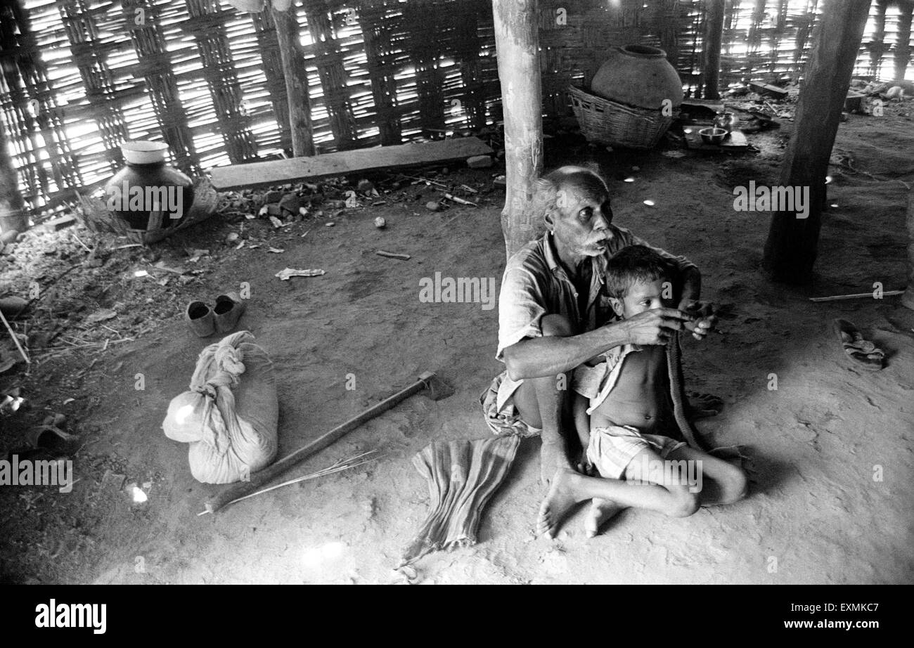 Father and child inside a hut in a village on the Maharashtra Gujarat border India Asia Indian poverty father son man boy poor Stock Photo