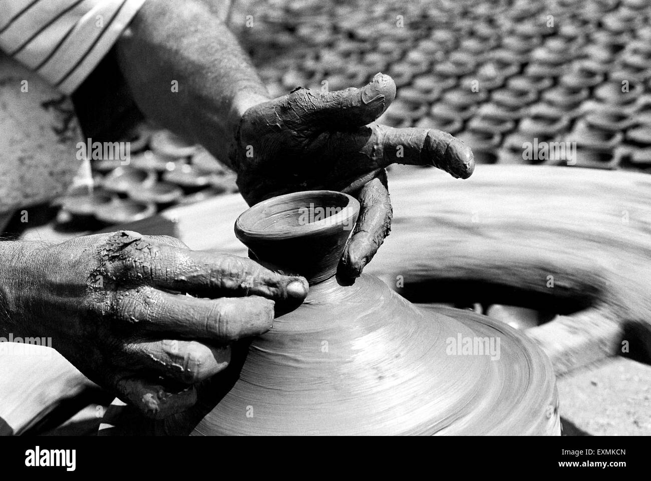 A potter sits on his potter's wheel as he makes diyas made out of clay for the Diwali festival in Kumbhaewada ; Dharavi Mumbai Stock Photo