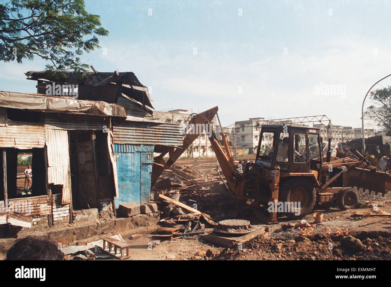 bulldozer demolishing illegal slum huts mumbai india Stock Photo