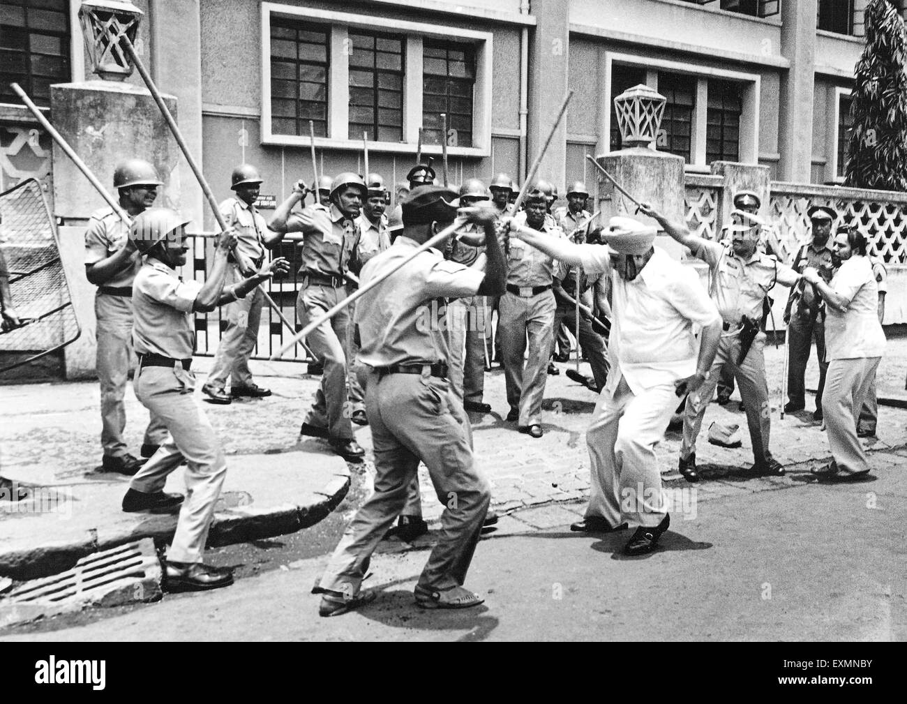 Policemen hitting man with sticks Bombay Mumbai Maharashtra India Stock Photo