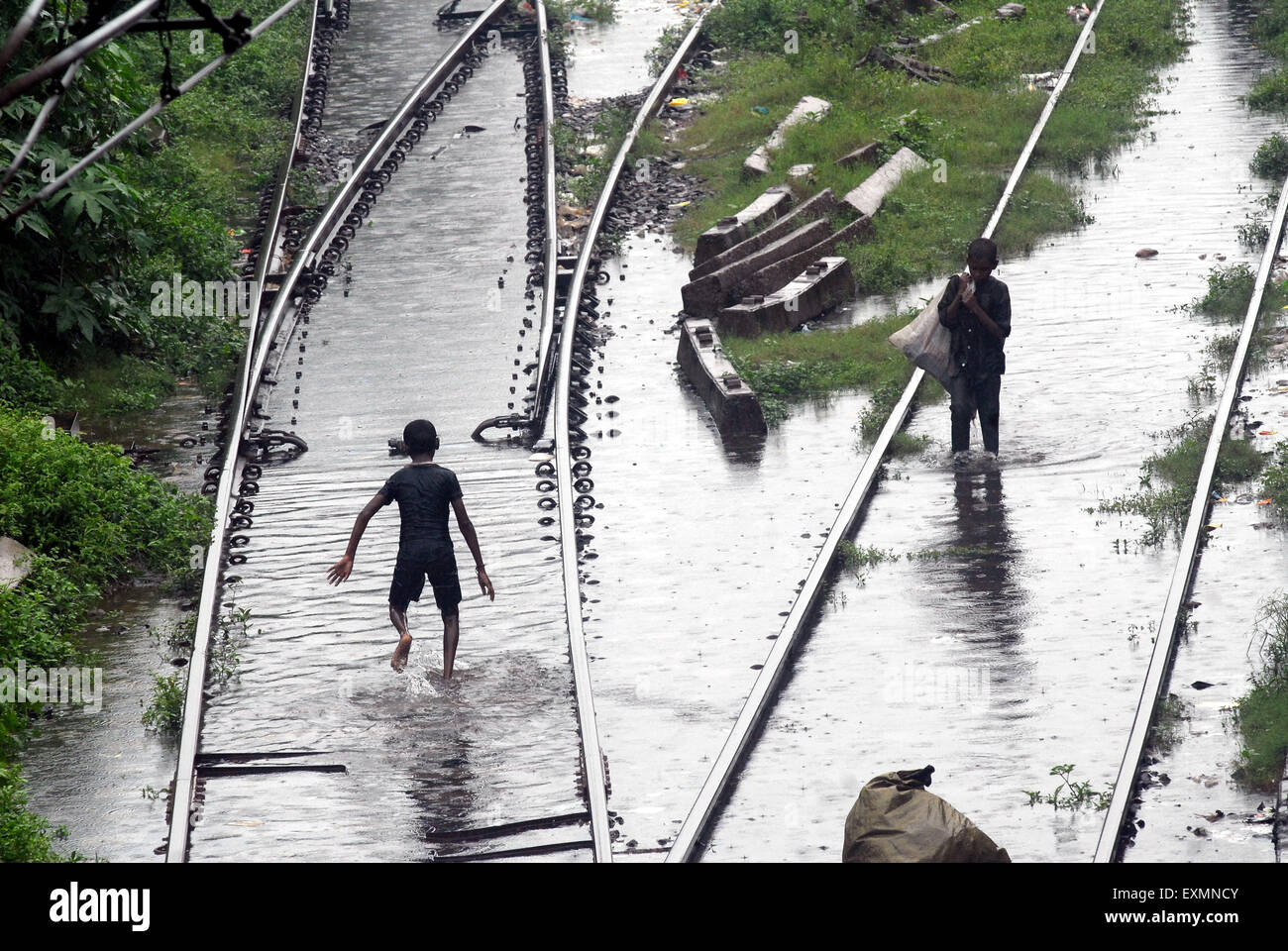 Children living in slums play in the flooded waters on the railway tracks caused due to heavy rains at Kurla Station Mumbai Stock Photo