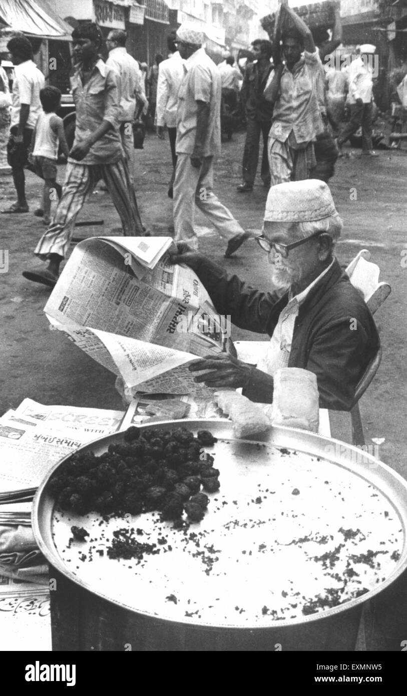 old man reading newspaper street food vendor mumbai india Stock Photo