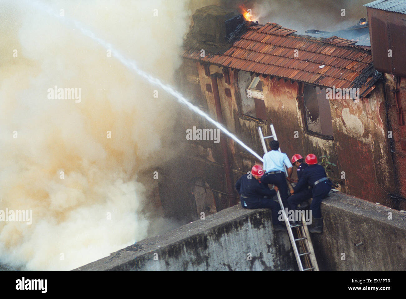 Fire brigade men spraying water to control fire mumbai India Stock Photo