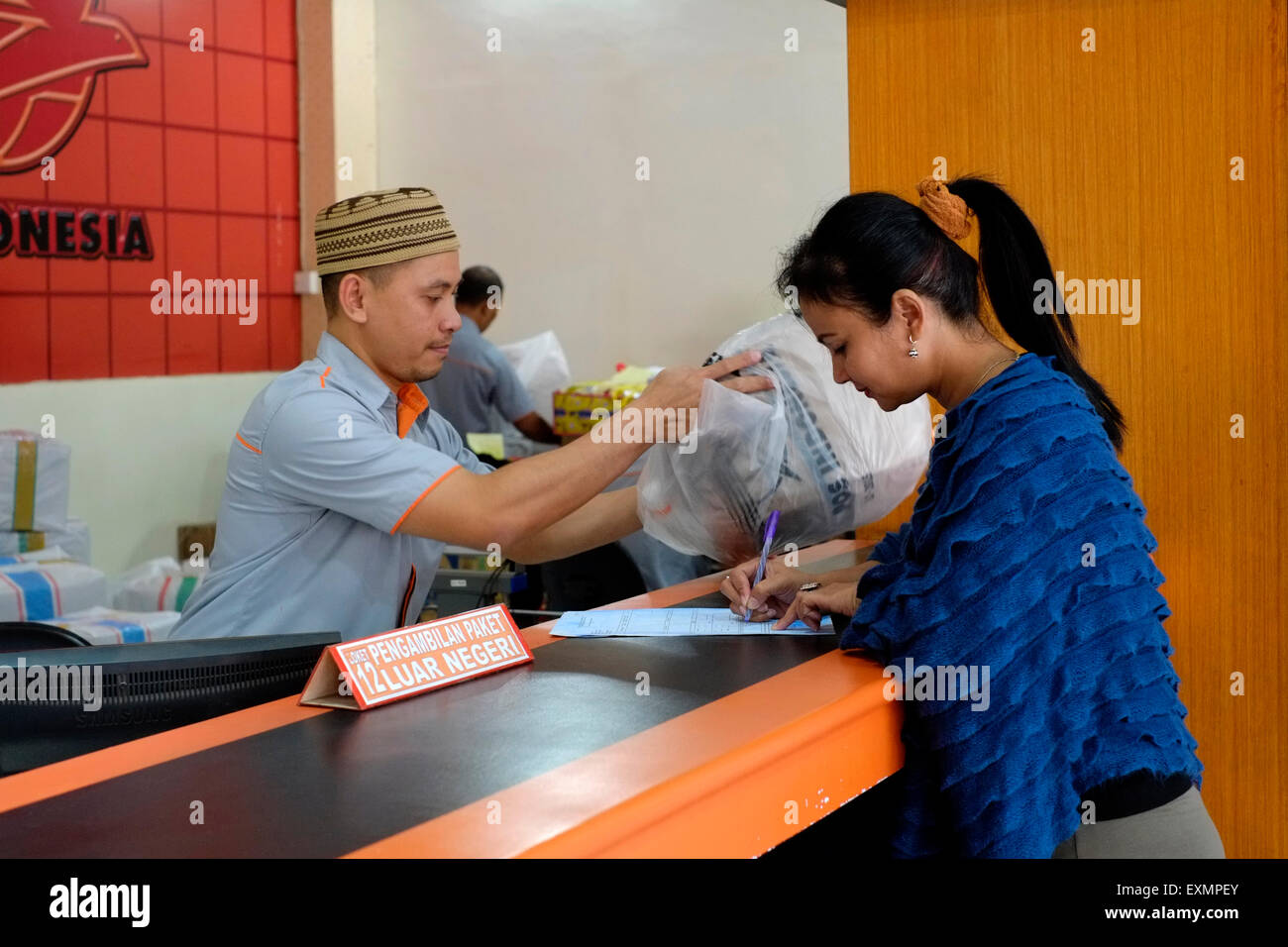 female customer signing for a delivery at the main post office in malang java indonesia Stock Photo