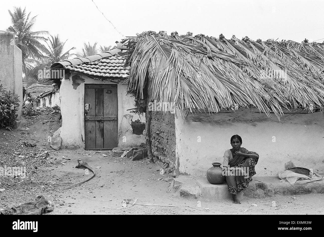 women with water pot sitting in front of her rural house at Hemmaragala village near Nanjangud in Mysore district Karnataka India Stock Photo