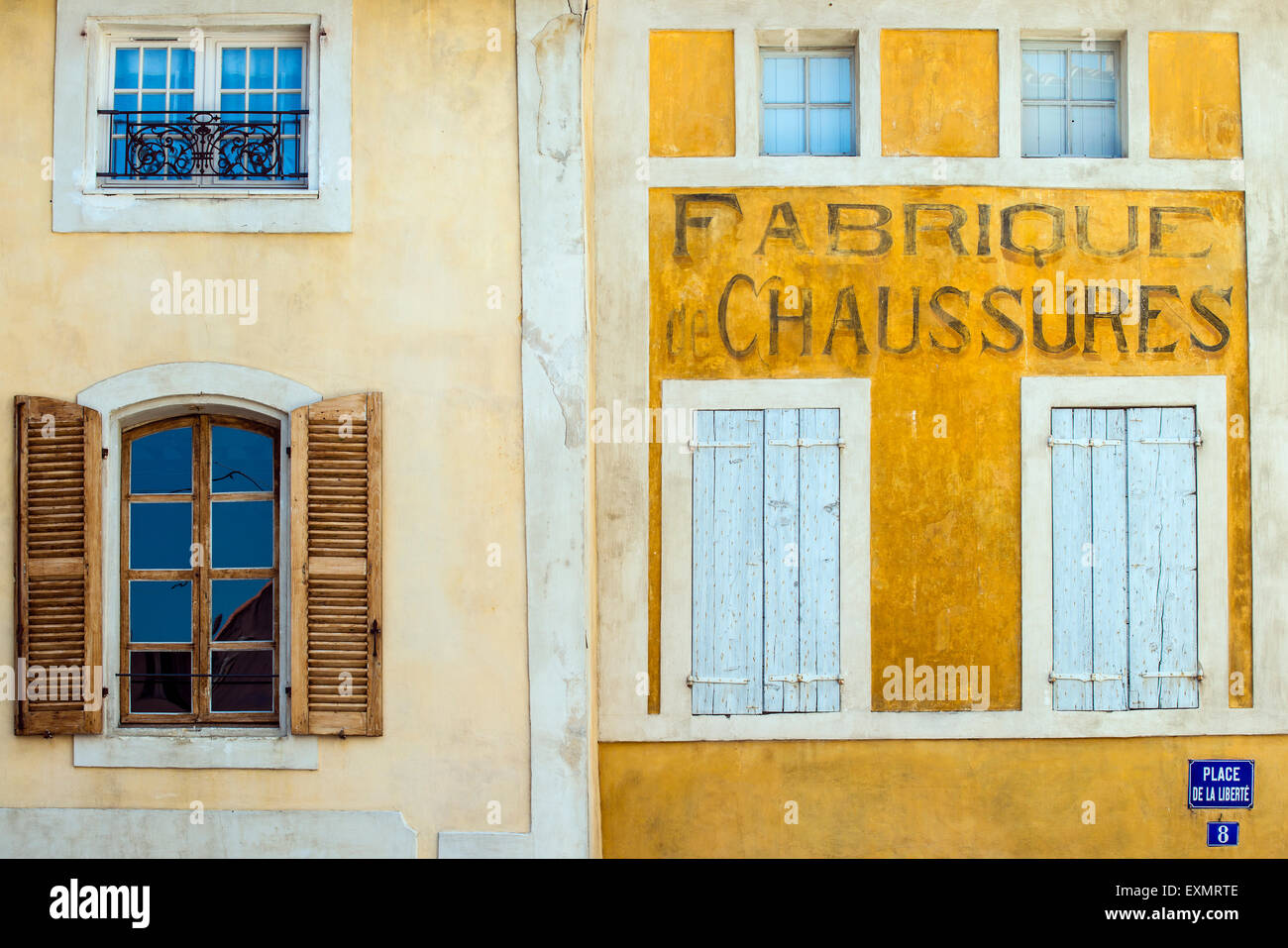 Old painted shop sign on the building facade, L’Isle-sur-la-Sorgue, Provence, France Stock Photo