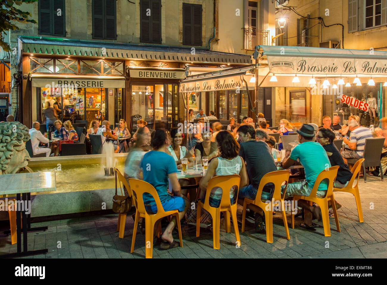 Night view of a Brasserie cafe restaurant with people seated outside at tables, Carpentras