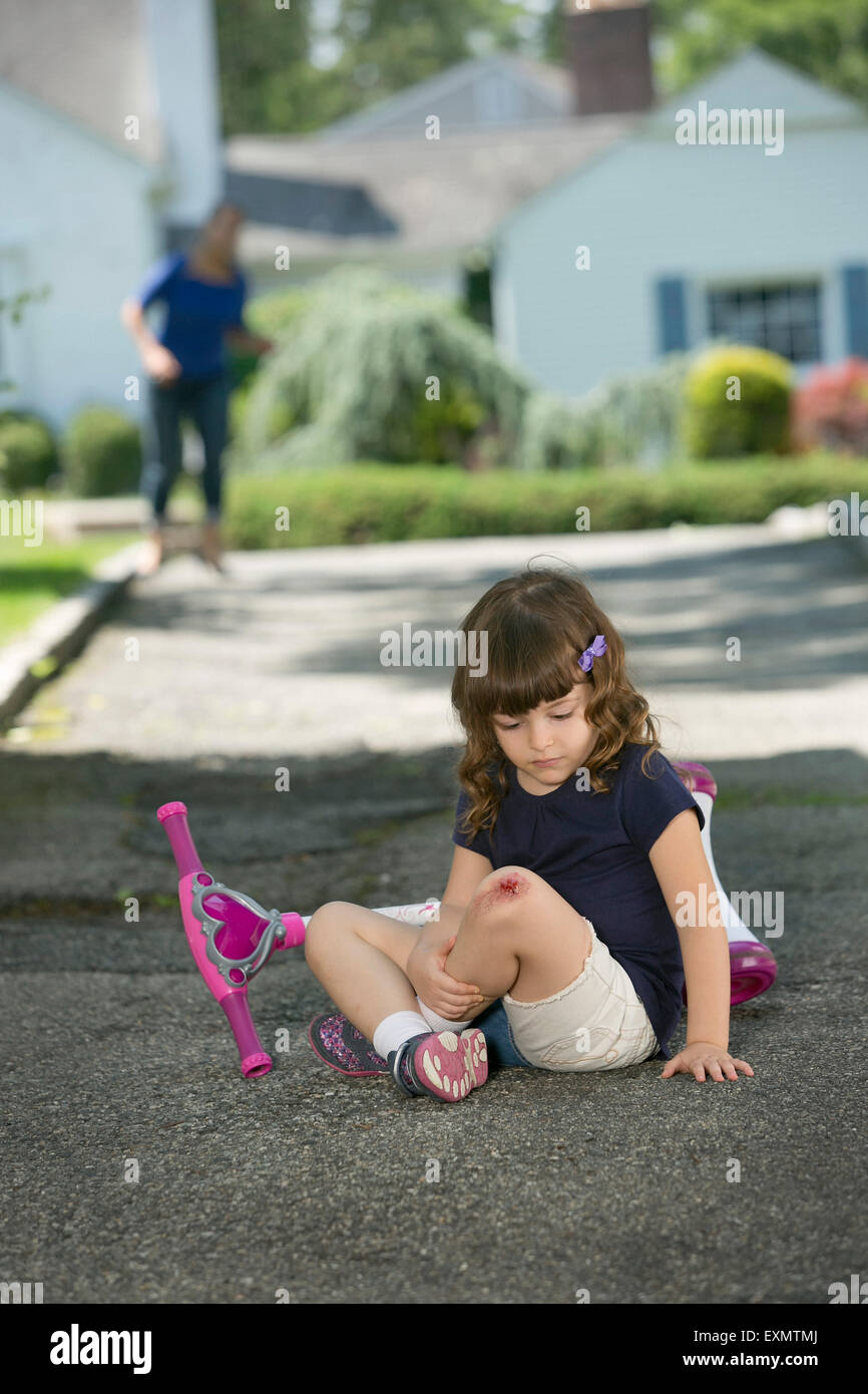 Young girl - 6-7 with skinned knee.  This is a model, wound is fake - make-up was used.  Model released. Stock Photo