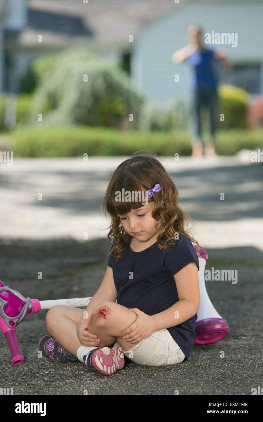 Young girl - 6-7 with skinned knee.  This is a model, wound is fake - make-up was used.  Model released. Stock Photo