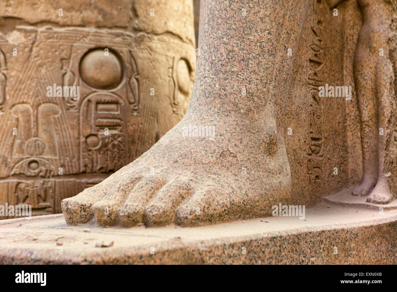 Ancient carvings surrounding a male foot sculpture with the smaller female form behind at the