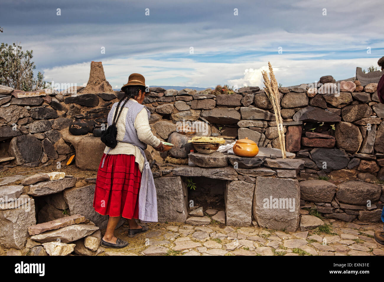 Older Woman demonstrates how to make potato bread in an outdoor oven in the high Andes of Peru. Stock Photo