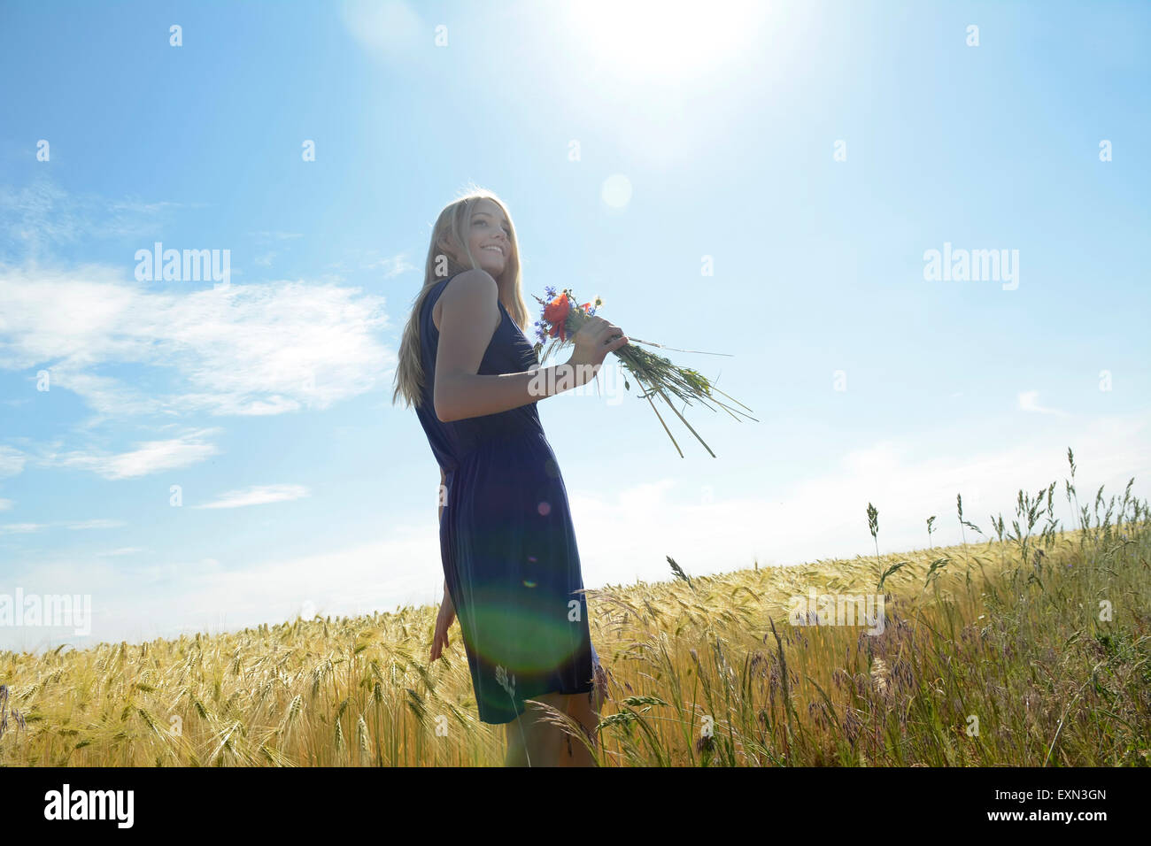 Smiling young woman with bunch of field flowers in a rye field Stock ...