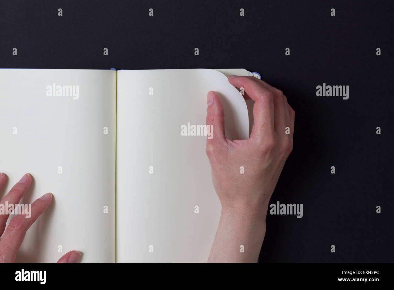 Woman turning page of blank note book Stock Photo