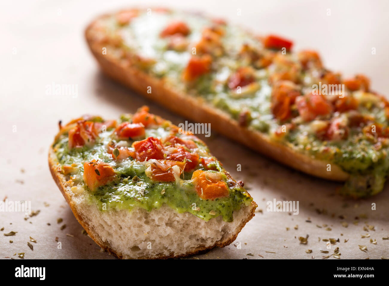 Close up of one bitten Baguette with pesto and spread oregano Stock Photo