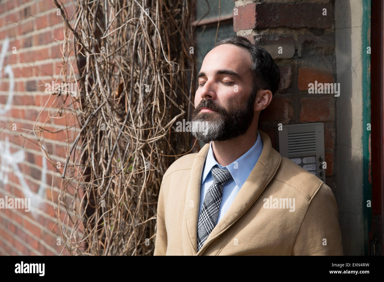 Fashionable man with grey beard leaning at door Stock Photo