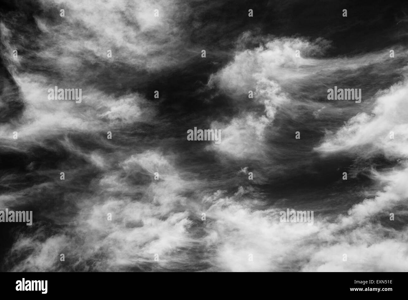 White clouds against a dark sky in monochrome picture. Stock Photo