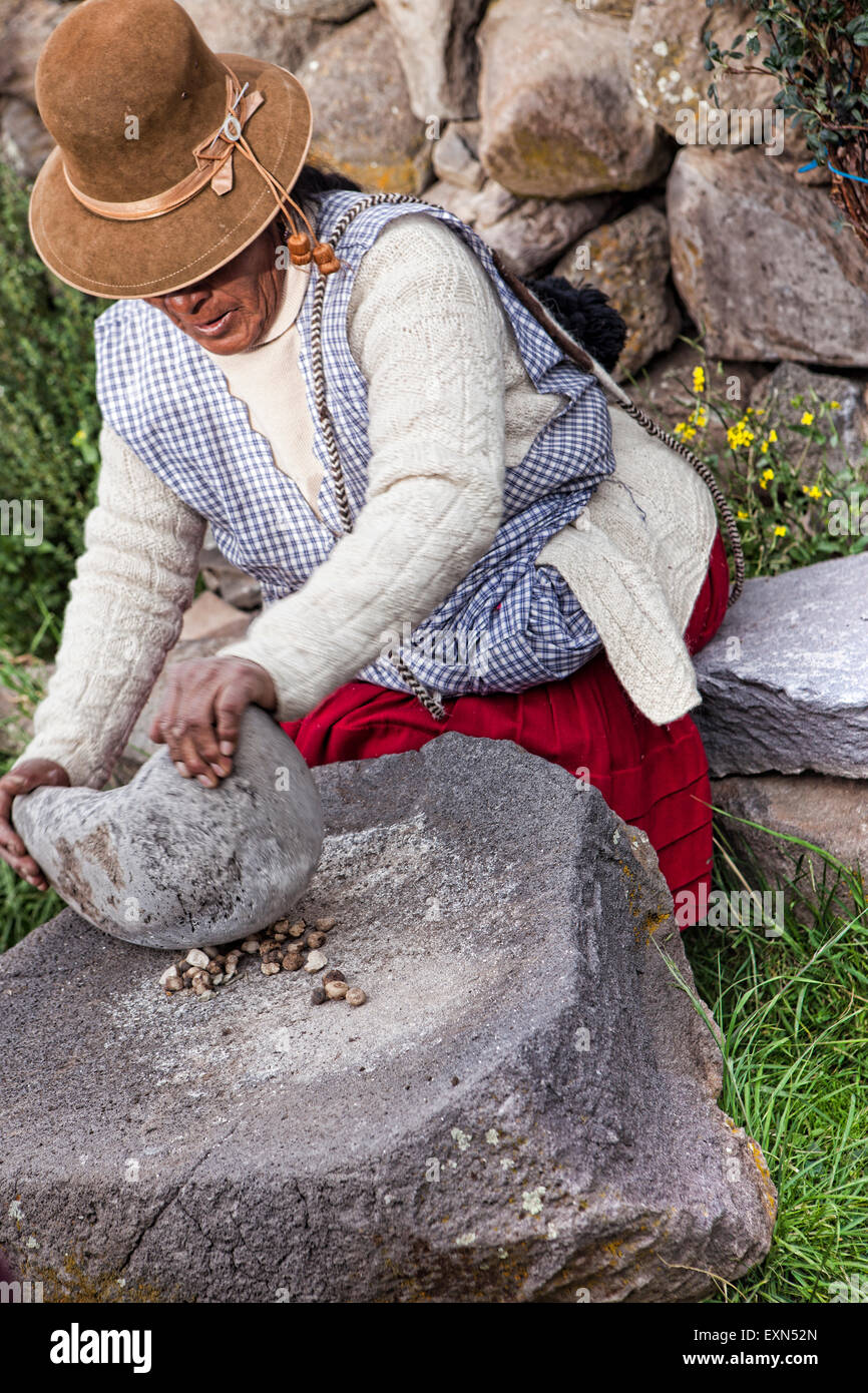 Older traditional Peruvian farm woman demonstrates how to grind potatoes into flour Stock Photo