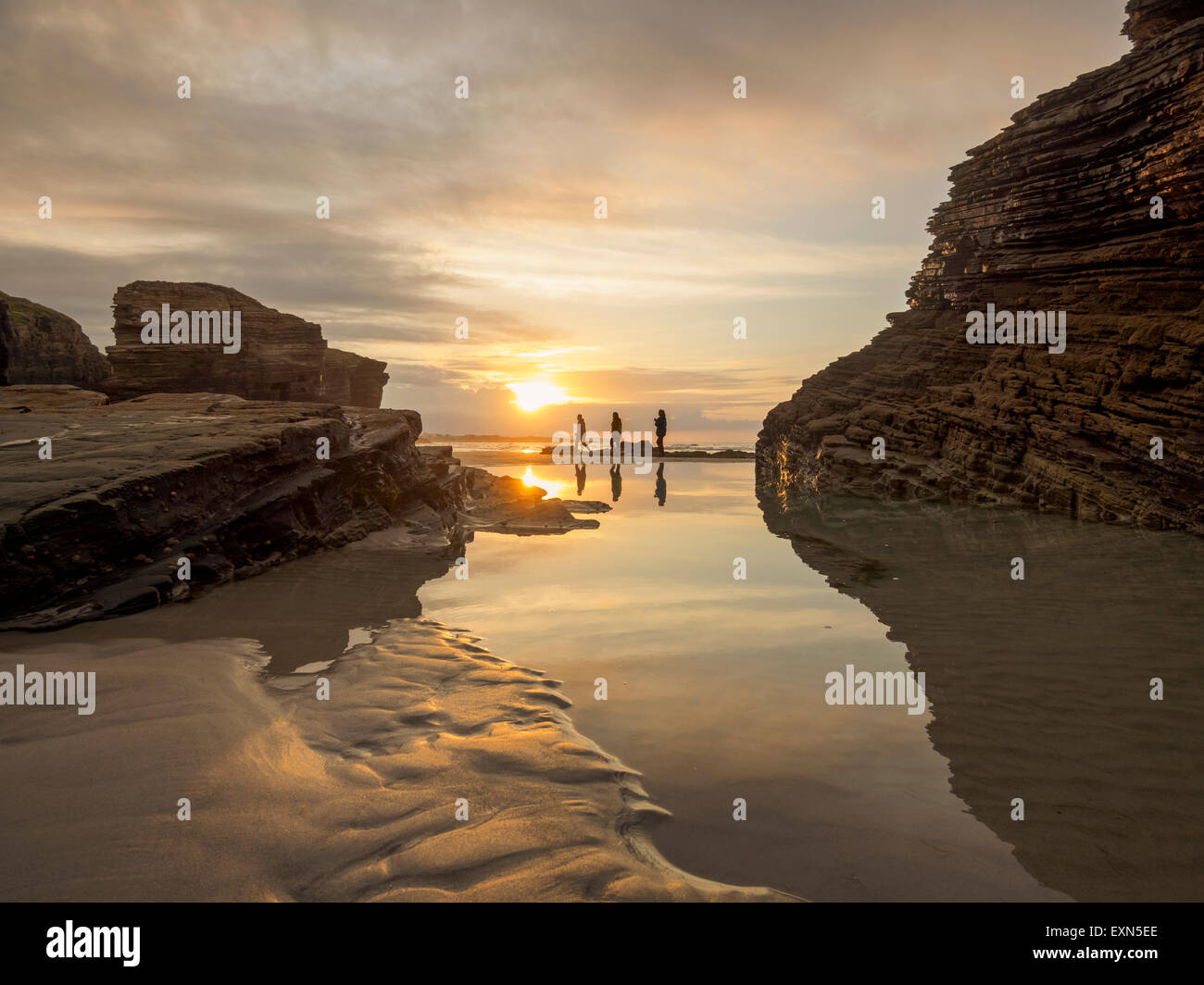 Spain, Galicia, Ribadeo, Playa de Aguas Santas at sunset, small persons at beach Stock Photo