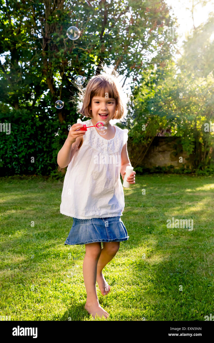 Little girl playing with soap bubbles in a garden Stock Photo - Alamy