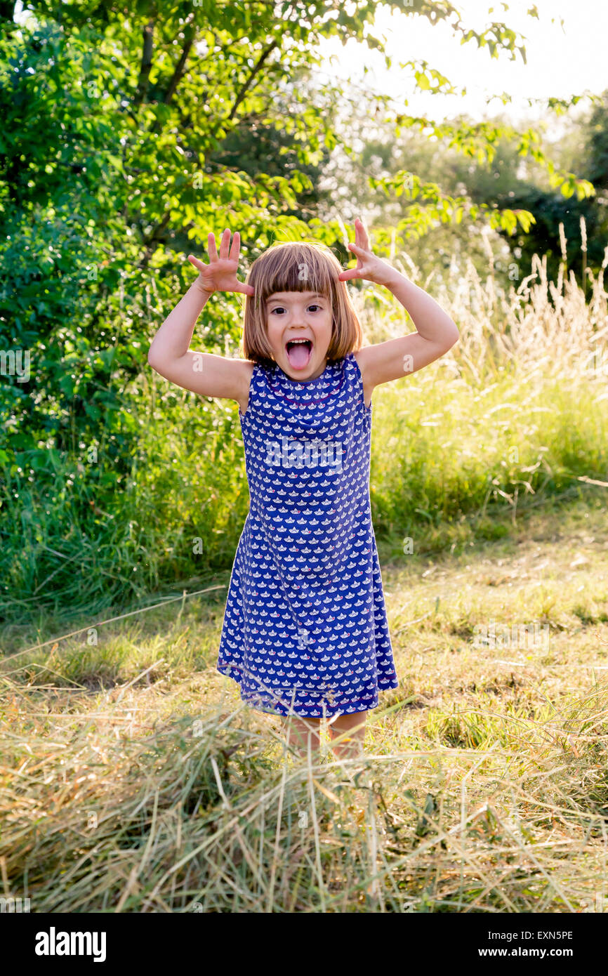 Portrait of little girl standing in hay field making faces Stock Photo