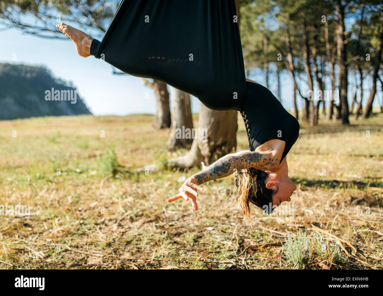 Woman practicing aerial yoga outdoors Stock Photo