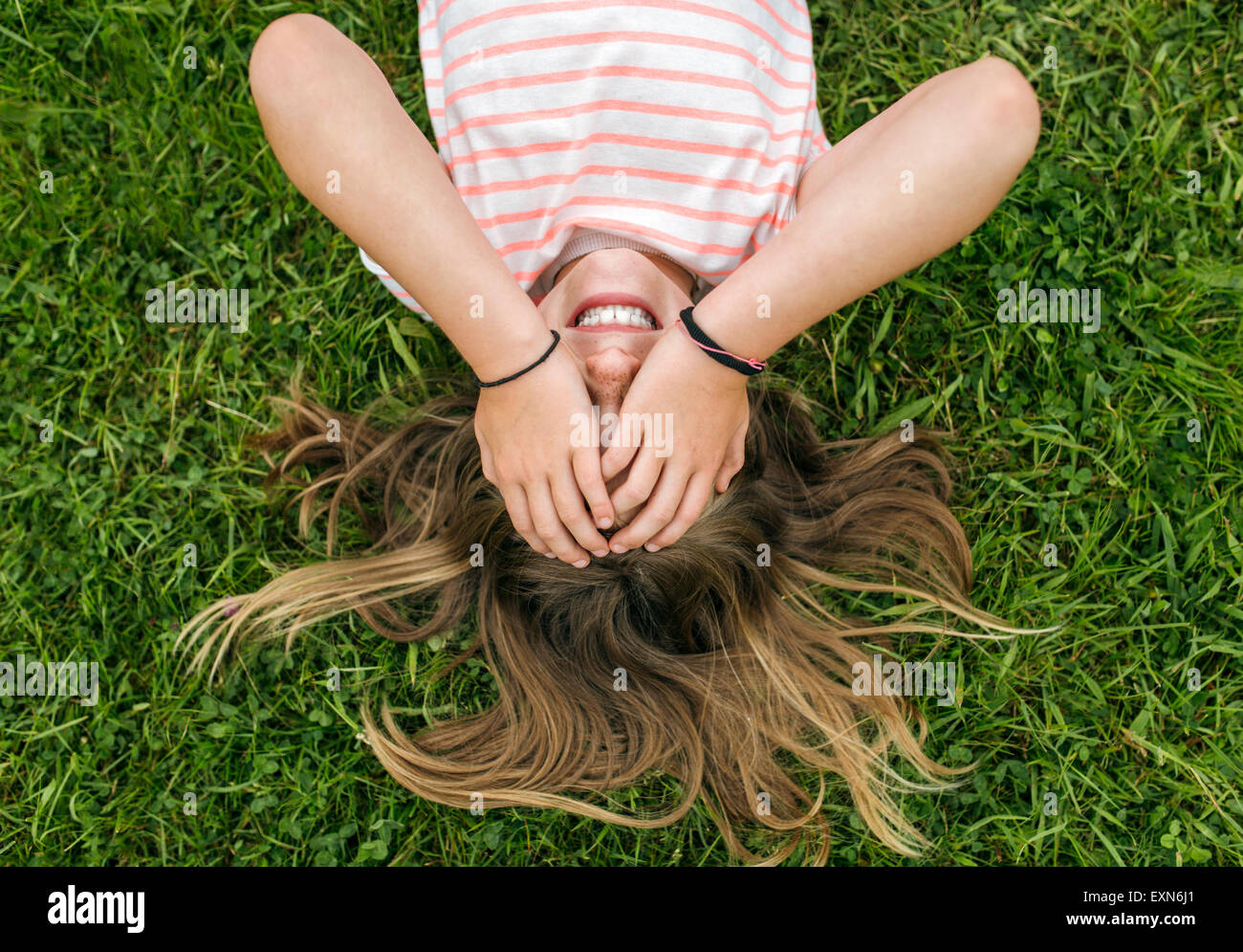 Girl lying on a meadow covering eyes with her hands Stock Photo - Alamy