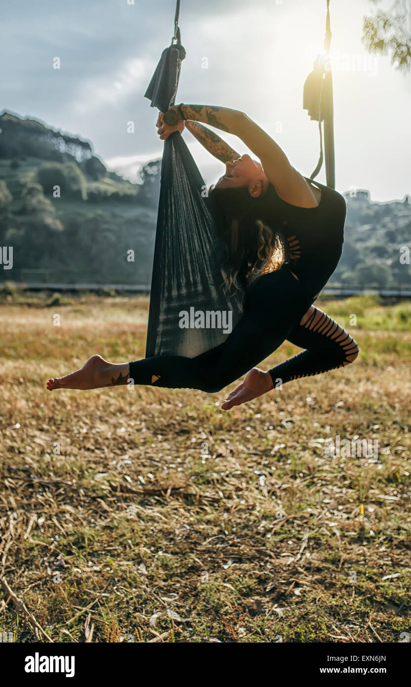 Woman doing aerial yoga outdoors Stock Photo