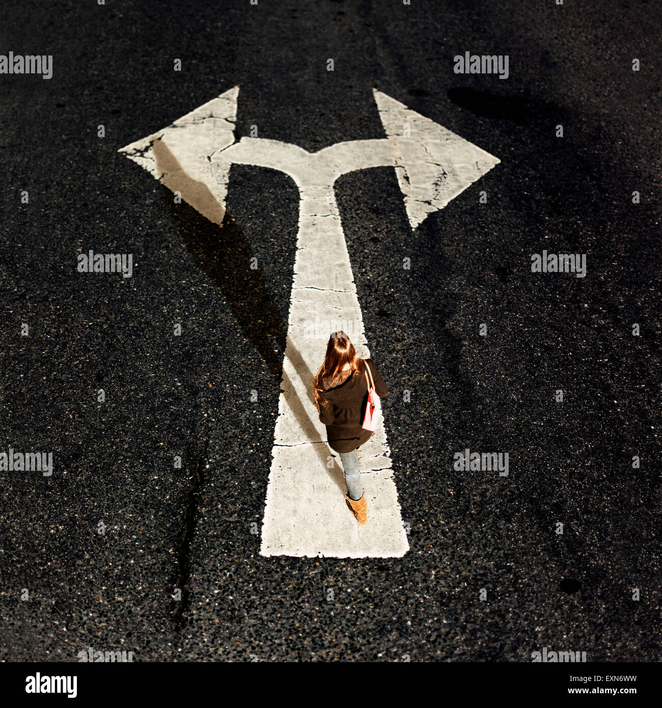 Woman walking on directional arrow of a road Stock Photo