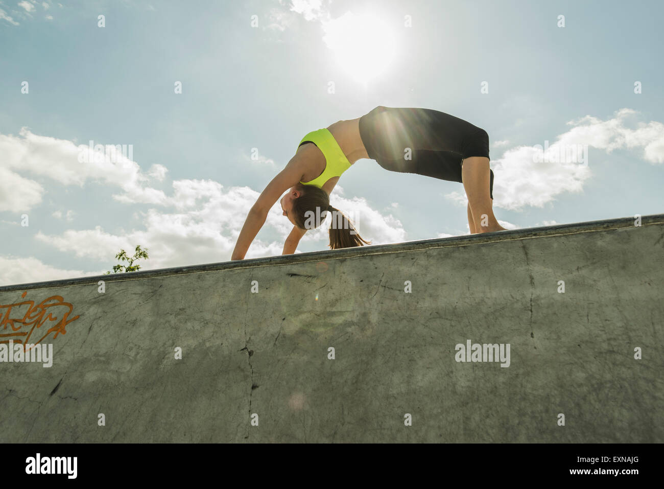 Young woman in bridge position on a wall Stock Photo