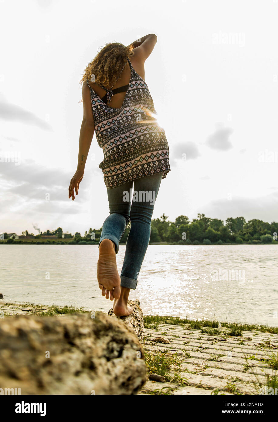 Young woman balancing on log by the riverside Stock Photo - Alamy