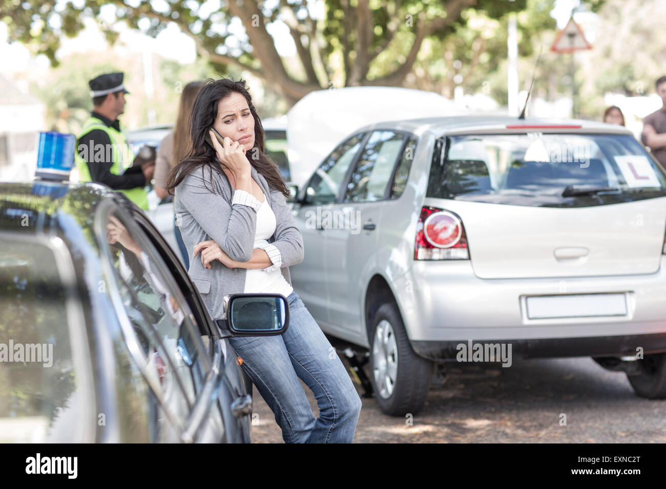 Woman on cell phone at car accident scene Stock Photo