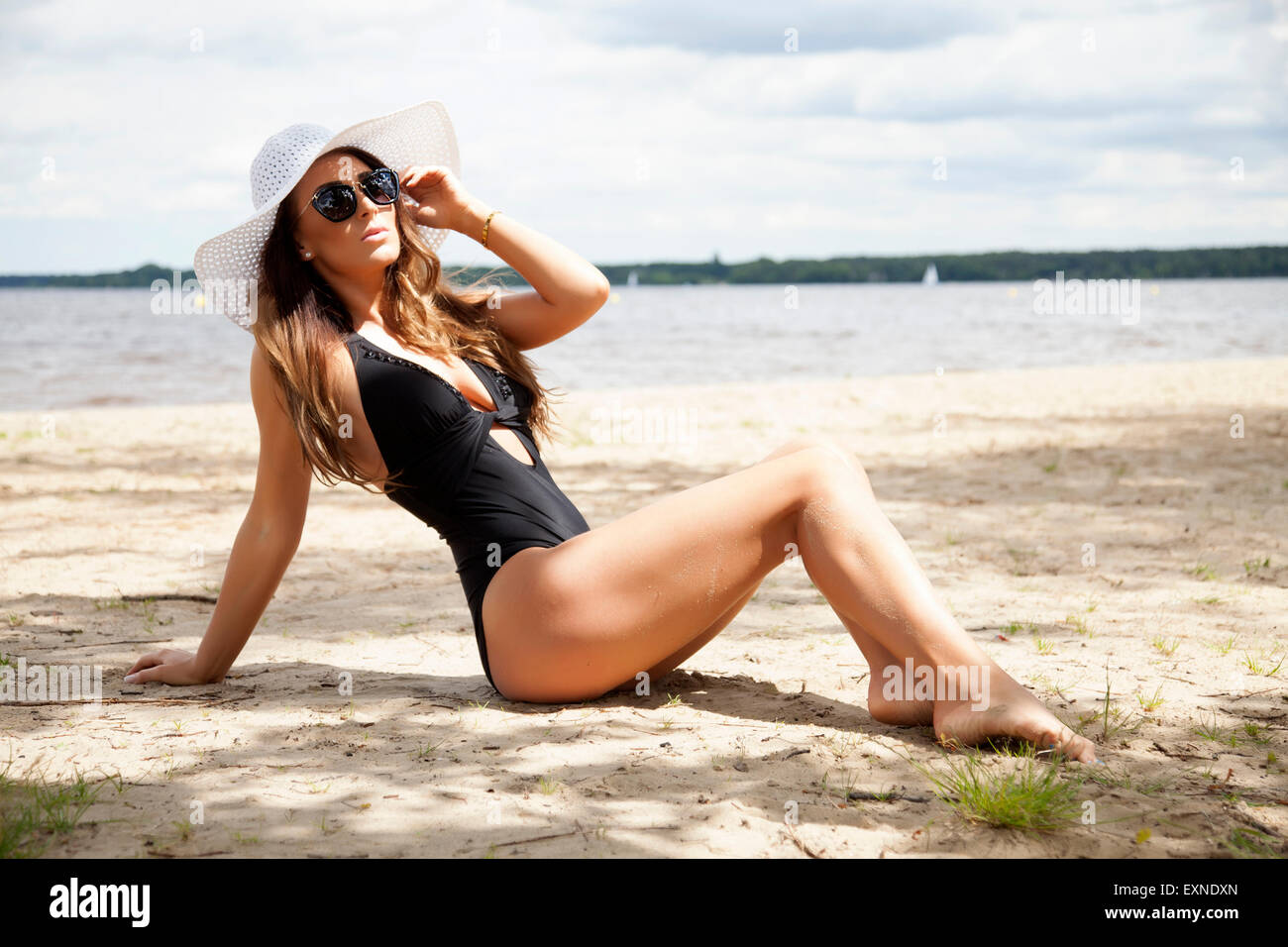 Young adult beautiful sensuality sexy and attractive brunette pretty woman in black swimwear dress and white hat and sunglasses  Stock Photo