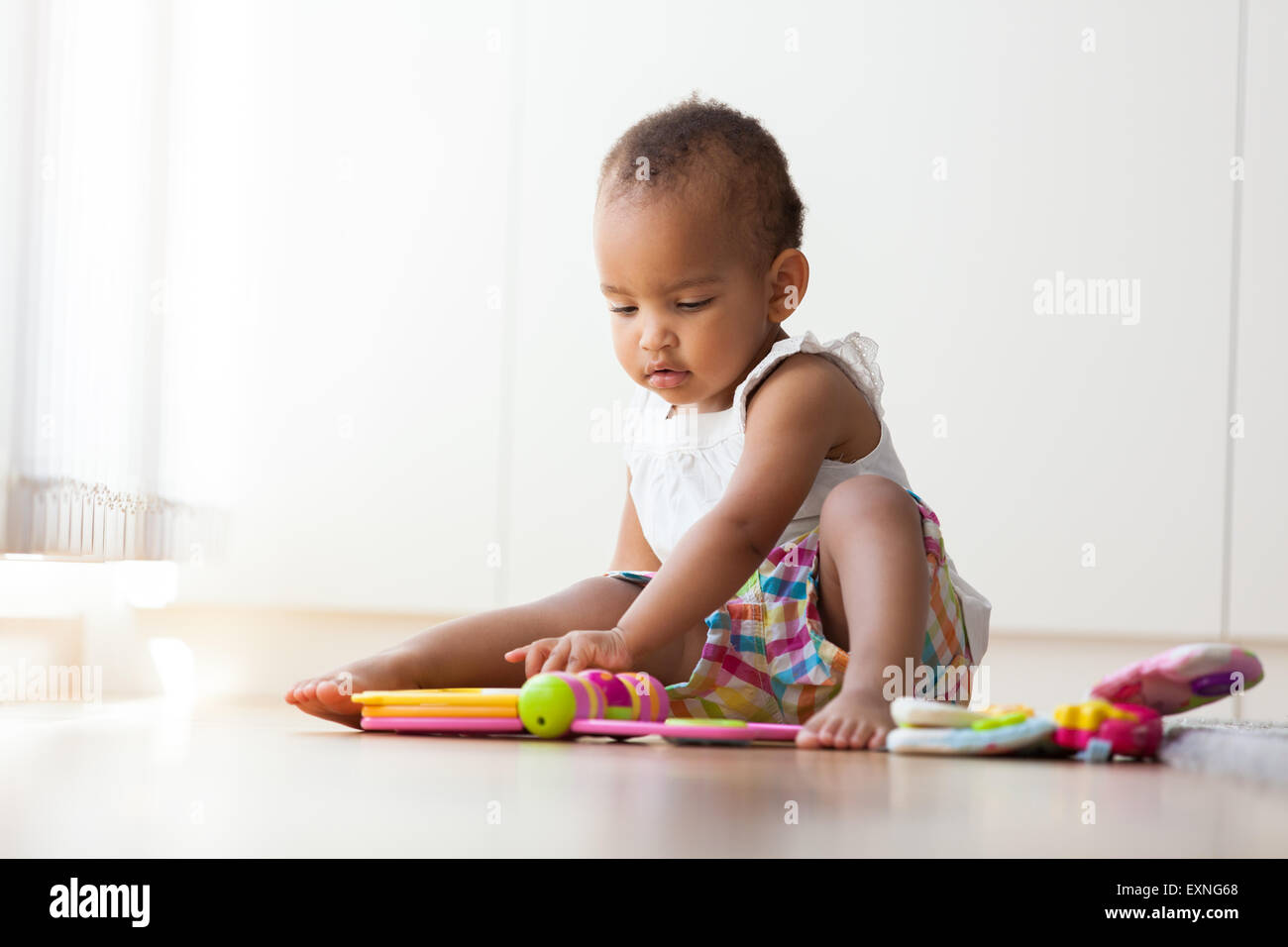 Portrait of little African American little girl sitting on the floor and playing  - Black people Stock Photo