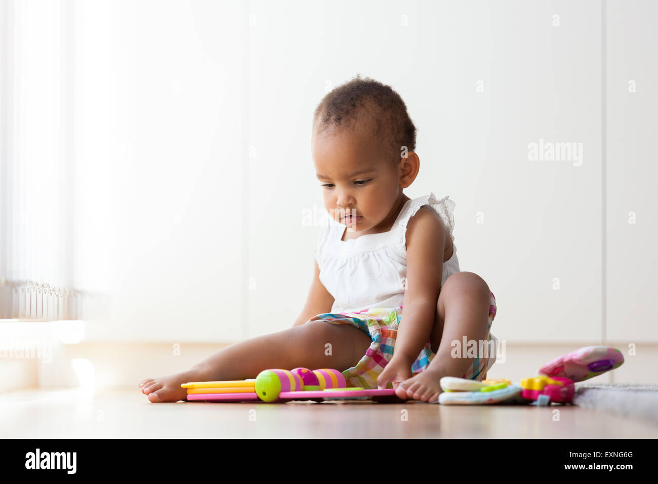 Portrait of little African American little girl sitting on the floor and playing  - Black people Stock Photo