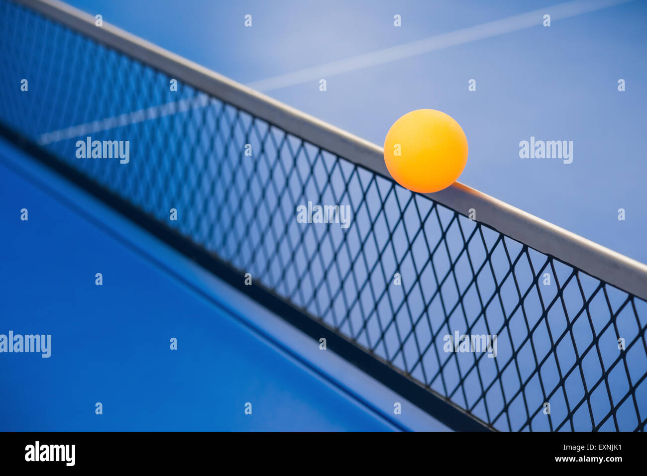 yellow ball hits the racket on a blue pingpong table Stock Photo