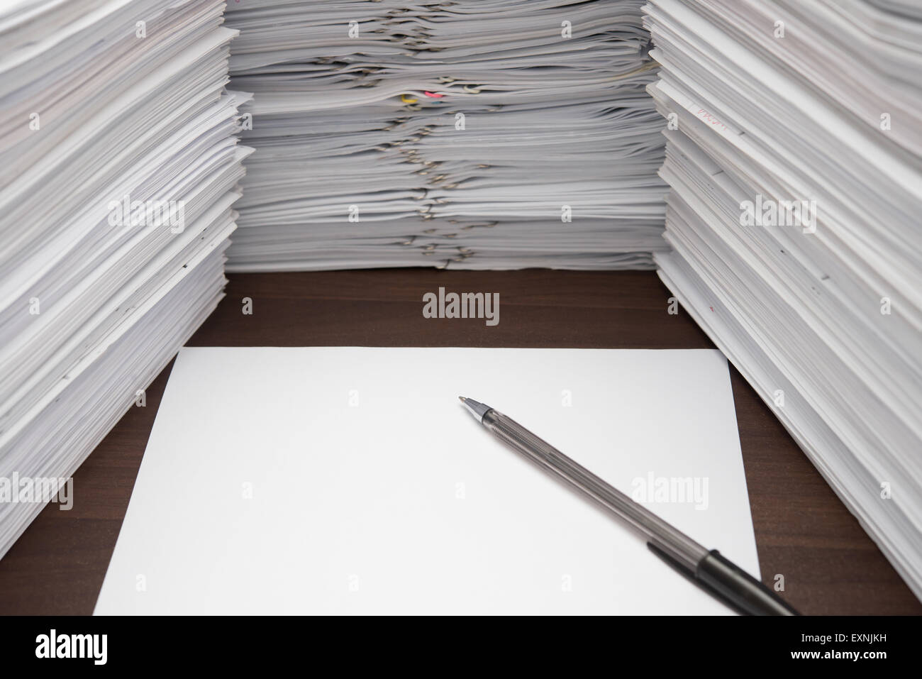 pen and blank paper besides piles of documents Stock Photo