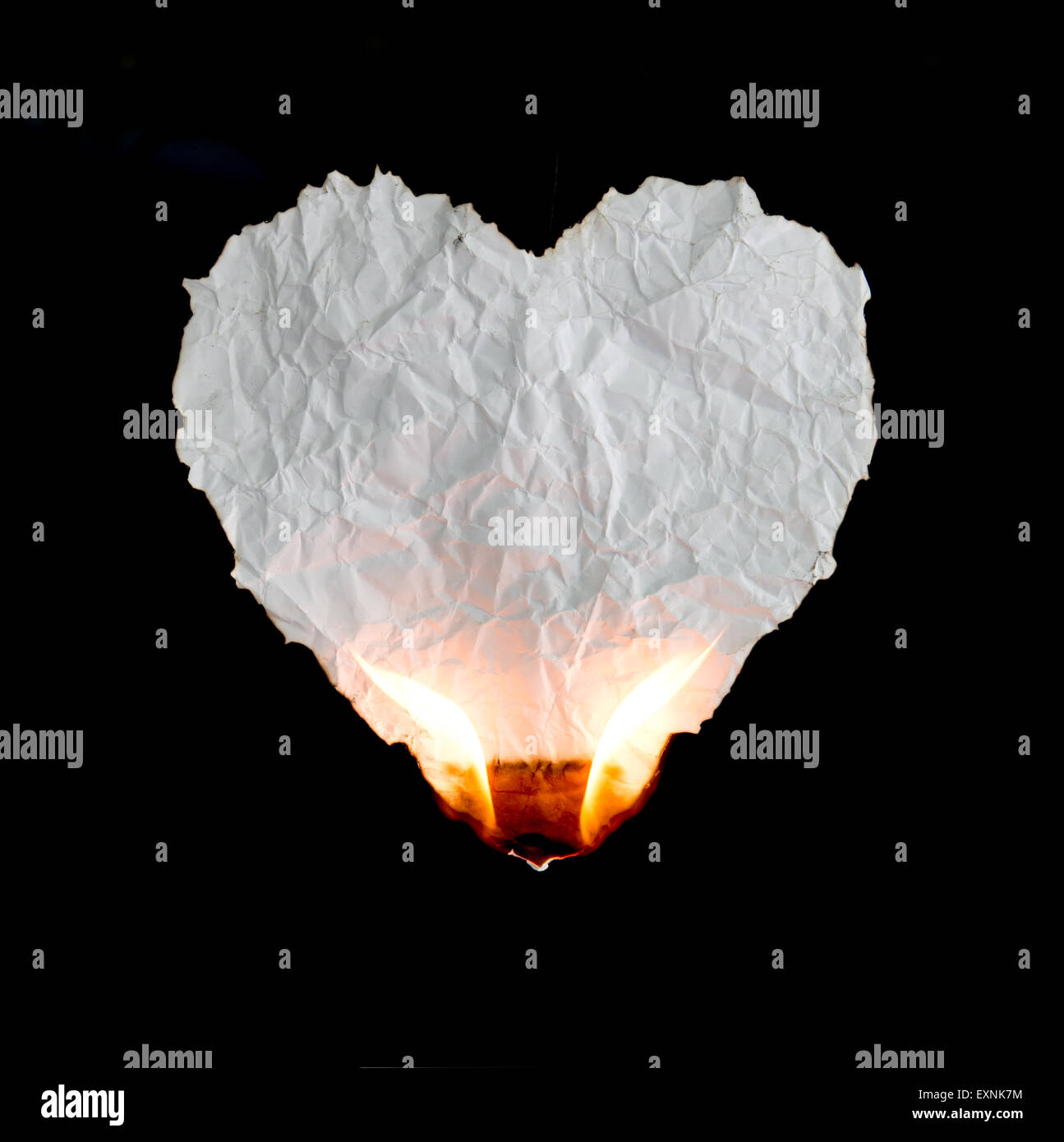 crumpled heart shape paper burning on black background Stock Photo