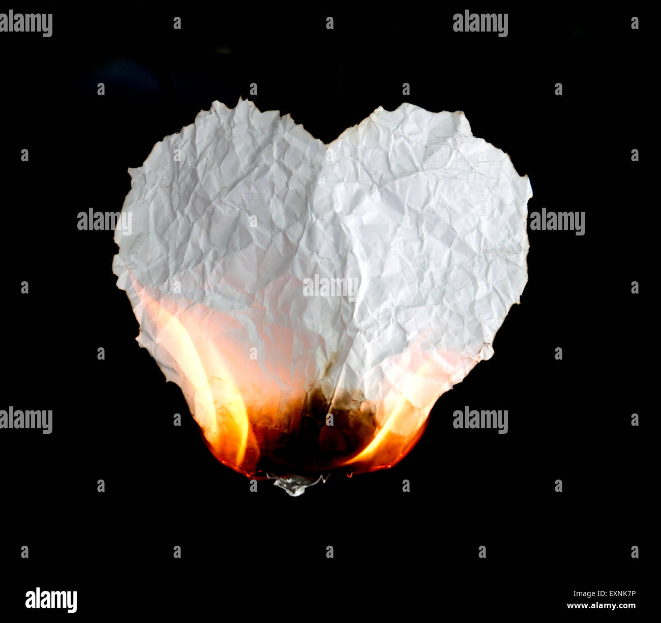 crumpled heart shape paper burning on black background Stock Photo