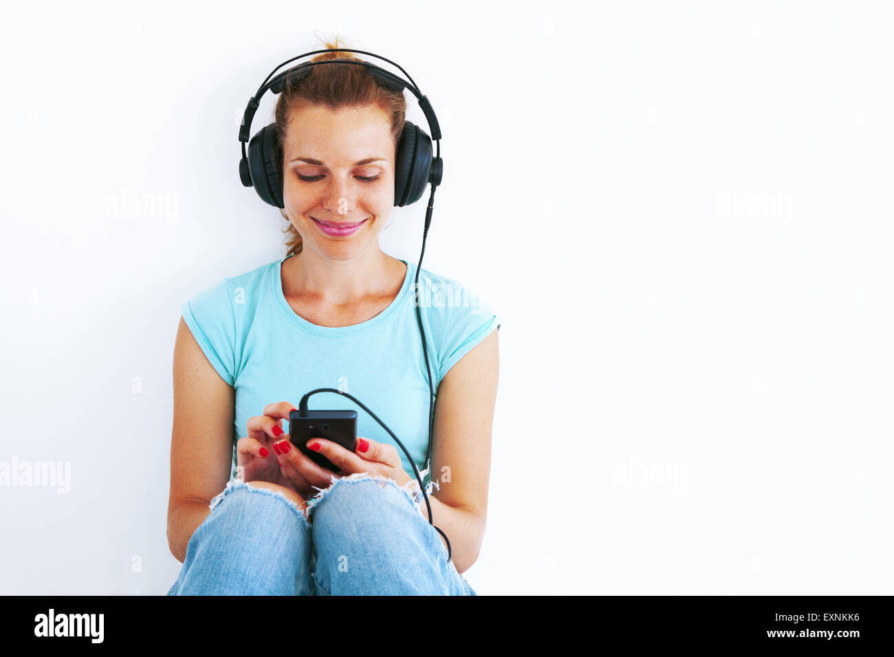 Young woman in casual dress listening music with headphones. Stock Photo