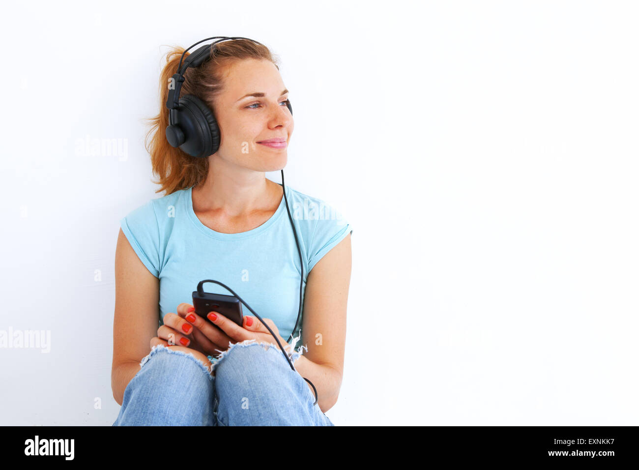 Young woman in casual dress listening music with headphones. Stock Photo