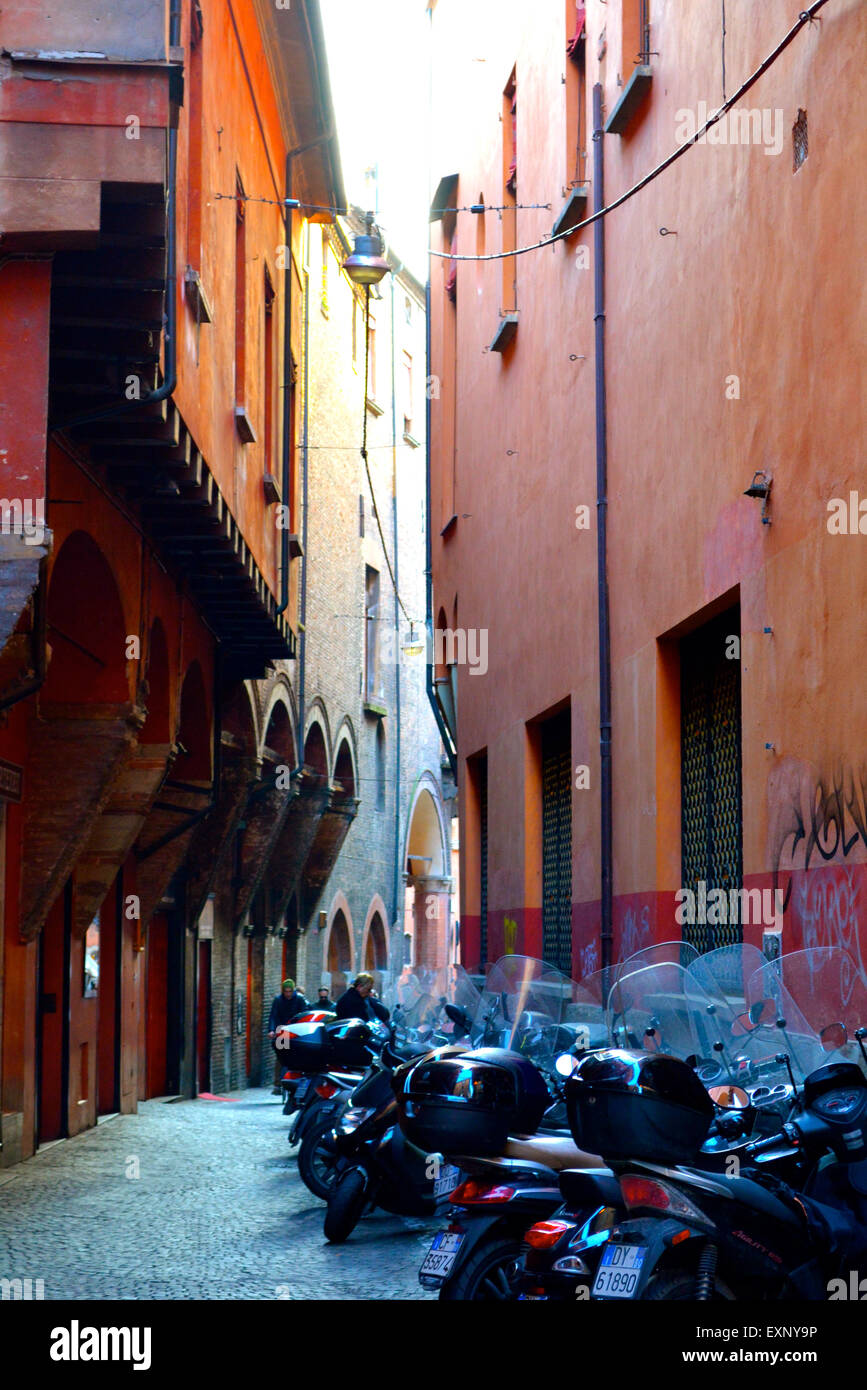Motorbikes parked on a typical red narrow street in Bologna, Italy Stock Photo
