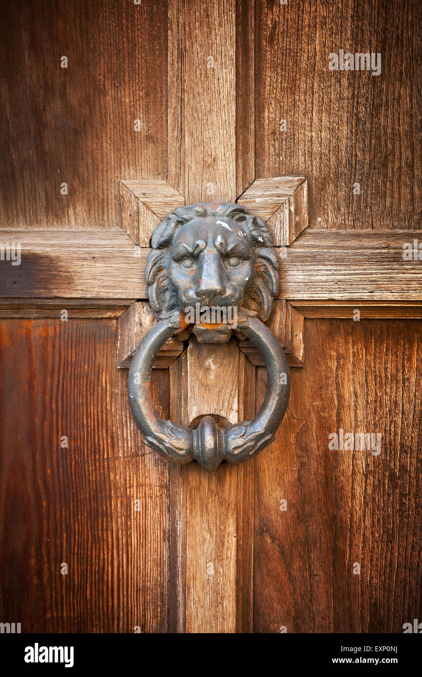 Old doorknob in shape of lion head with ring on vintage wooden door Stock Photo