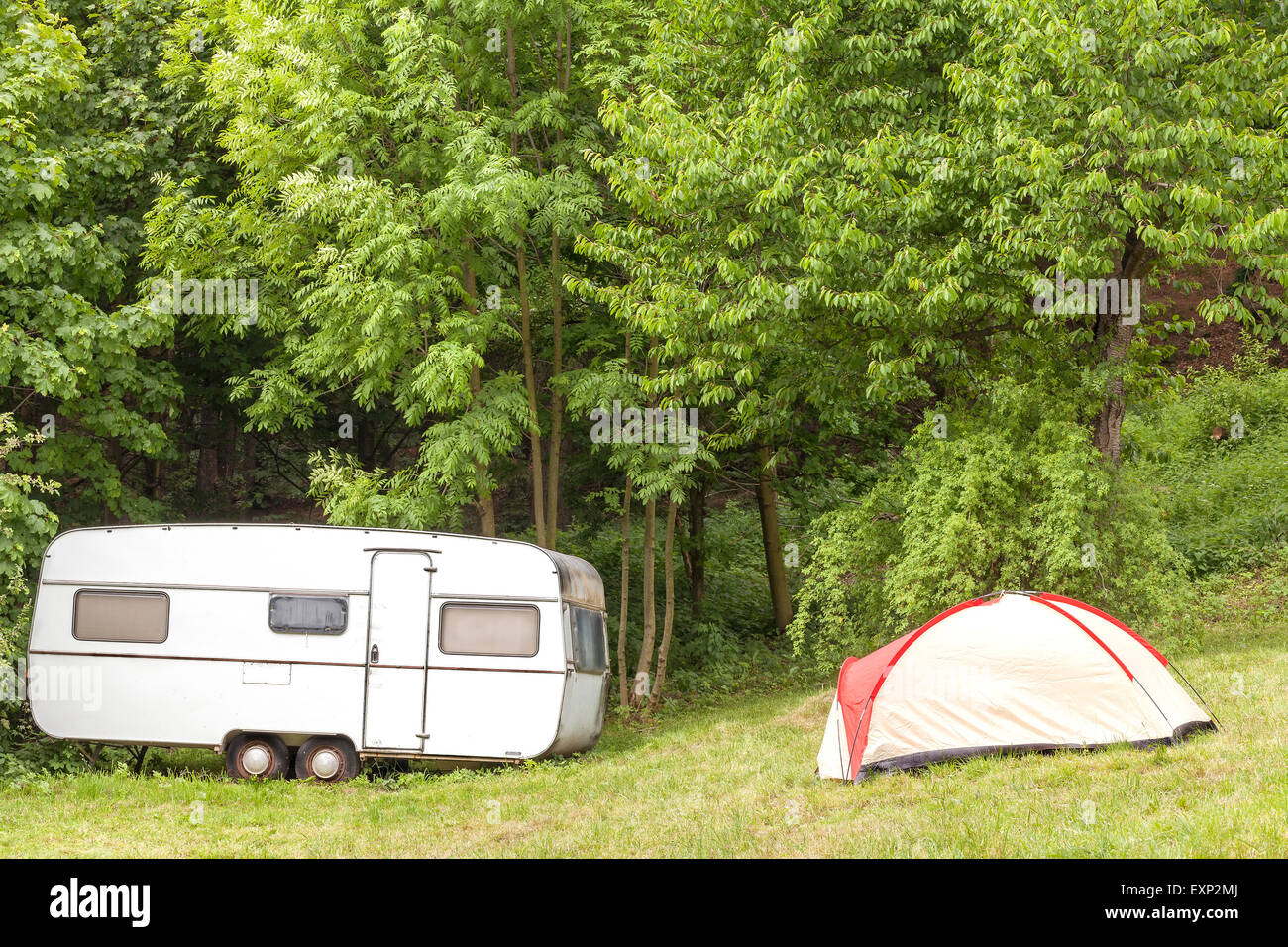 Old camping trailer and tent in the forest. Stock Photo