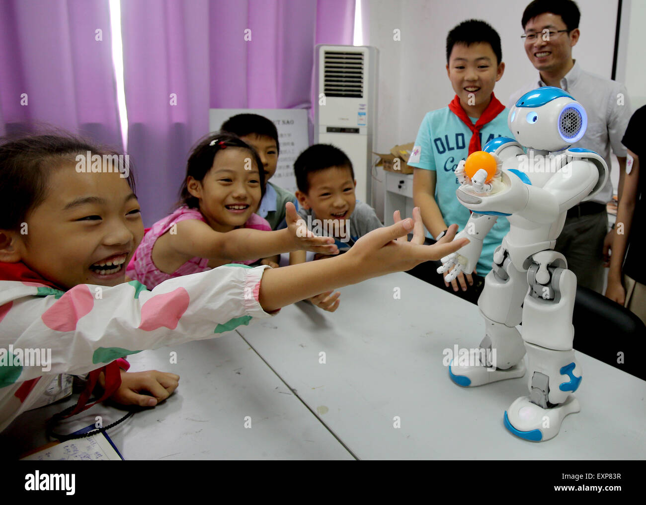 Shanghai, China. 16th July, 2015. Children interested in scientific invention meet Robot Nao at a robot laboratory in Shanghai Jiaotong University, east China, July 16, 2015. Nao is a 58-centimeter tall robot developed and manufactured by Aldebaran Robotics, a Paris-based company. Credit:  Liu Ying/Xinhua/Alamy Live News Stock Photo