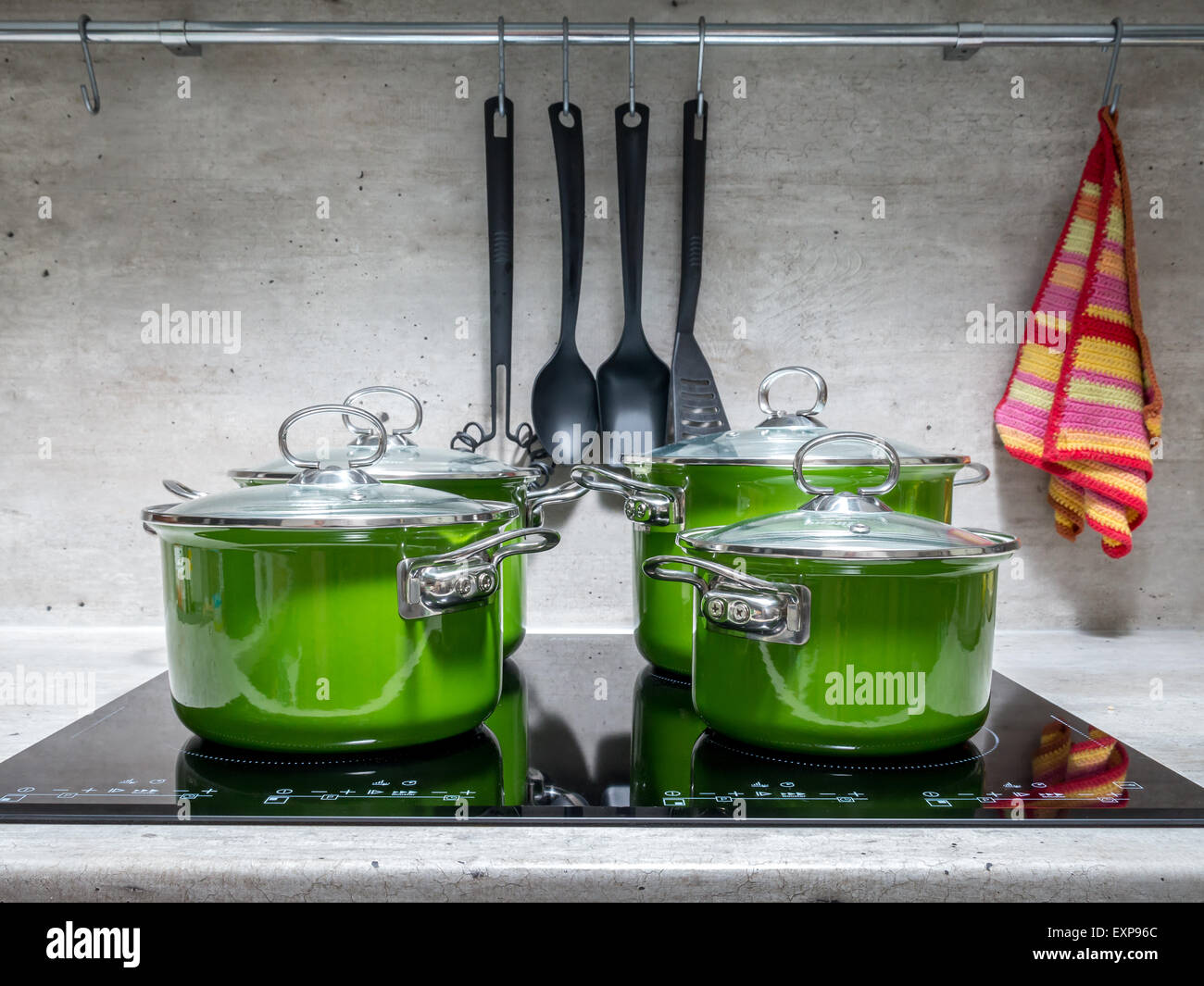 Four green enamel stewpots on black induction cooker Stock Photo