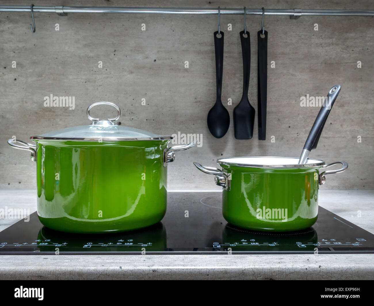 Two green enamel stewpots on black induction cooker Stock Photo