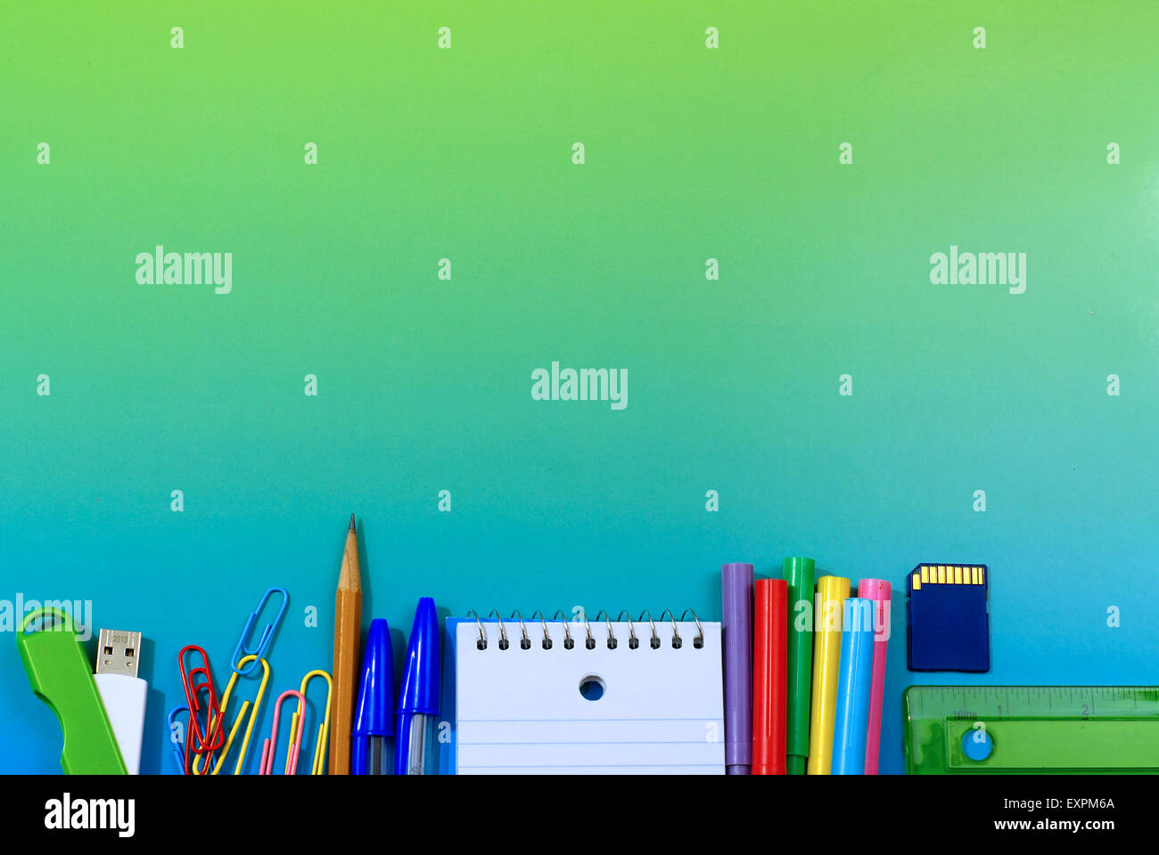 School or office supplies as a low border on a blue green background with copy space Stock Photo