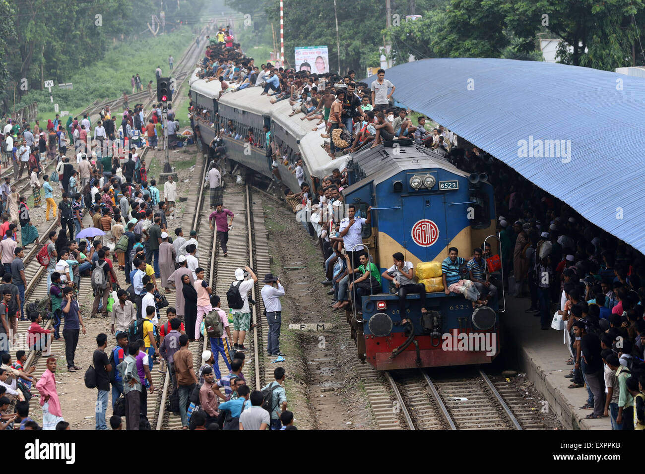 Dhaka, Bangladesh. 16th July, 2015. Bangladeshi passengers sit on the roof of a train, as they head to their homes to celebrate Eid al-Fitr in Dhaka, Bangladesh, Thursday, July 16, 2015. Hundreds of thousands of people working in Dhaka plan to leave for their home towns to celebrate with their family the upcoming Eid al-Fitr. Stock Photo